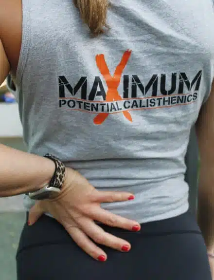 Woman with hand on lower back wearing Maximum Potential Calisthenics Singlet